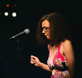 Maya Williams stands in front of a mic looking down